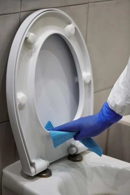 A person in protective gear sanitizing an office desk using fumigation equipment during daytime.